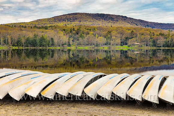 Photograph of canoes and a mountain overlooking the lake in springtime at North-South Lake in Haines Falls, New York.