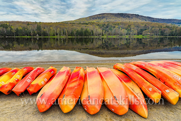 Photograph of kayaks and a mountain overlooking the lake in springtime at North-South Lake in Haines Falls, New York.