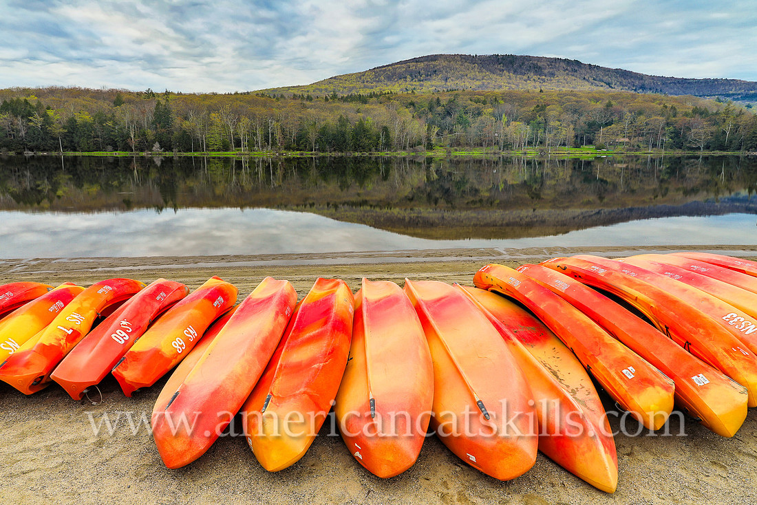 Photograph of kayaks and a mountain overlooking the lake in springtime at North-South Lake in Haines Falls, New York.