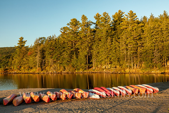 Photograph of a line of kayaks in the late afternoon on the beach of North-South Lake in the Catskills.