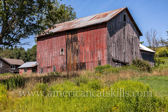 Photograph of an abandoned barn with fading red paint in Delaware County, New York.