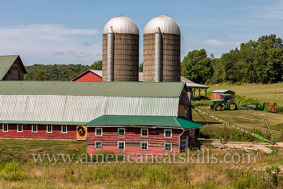 Photograph of a barn, silo and farm equipment on a farm in Delaware County, New York.