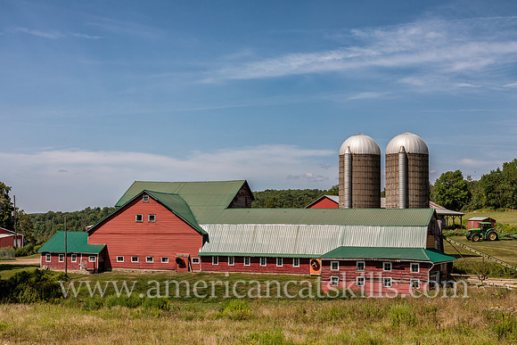 Photograph of a barn, silo and farm equipment on a farm in Delaware County, New York.