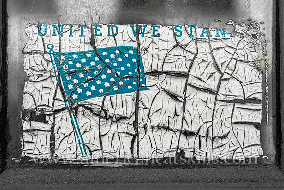 Located in the Stockade District of Kingston, this faded and cracked window decal depicts the American flag with the words “United We Stand.”