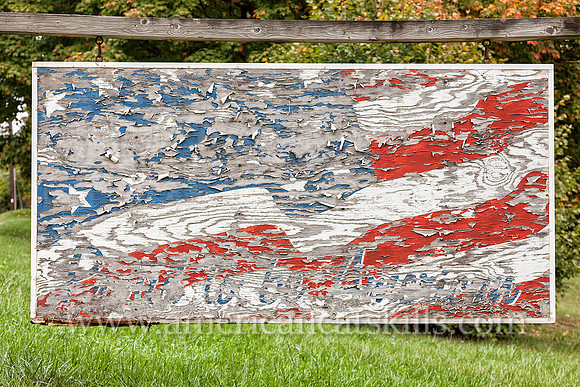 Abandoned and fading sign with waving American flag and the words “Proud to be American”; located at Ellenville in Ulster County, New York.