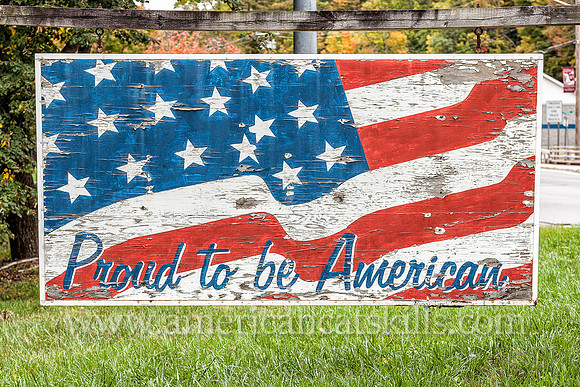 Abandoned and fading sign with waving American flag and the words “Proud to be American”; located at Ellenville in Ulster County, New York.