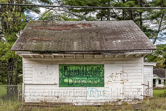 Abandoned white bungalow with sign on front for “Emerald Forest Bungalows” at Ellenville in Ulster County, New York.