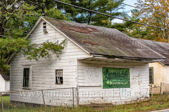 Abandoned white bungalow with sign on front for “Emerald Forest Bungalows” at Ellenville in Ulster County, New York.