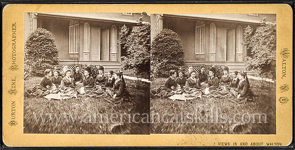 "Group portrait of women sitting on the grass in front of a house." Burton Hine, photographer.