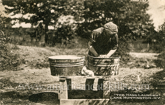 Vintage photograph titled "The Hand Laundry, Lake Huntington, N. Y." showing a young man washing his clothes in a tub.