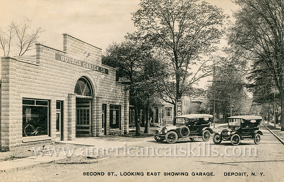 Vintage photograph titled "Second St., Looking East Showing Garage, Deposit, N. Y." showing a car garage and two cars parked in front.